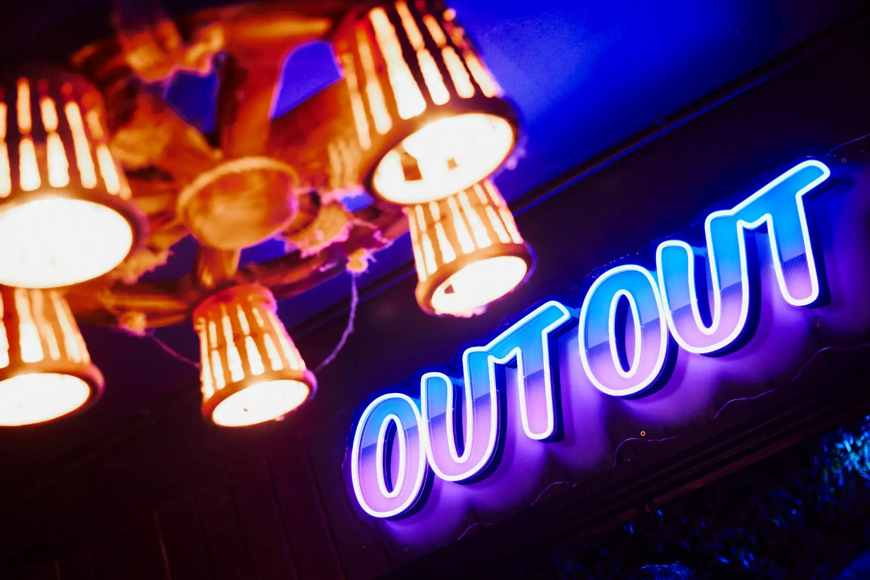 A large illuminated OutOut Plymouth nightclub sign and bright ceiling lights