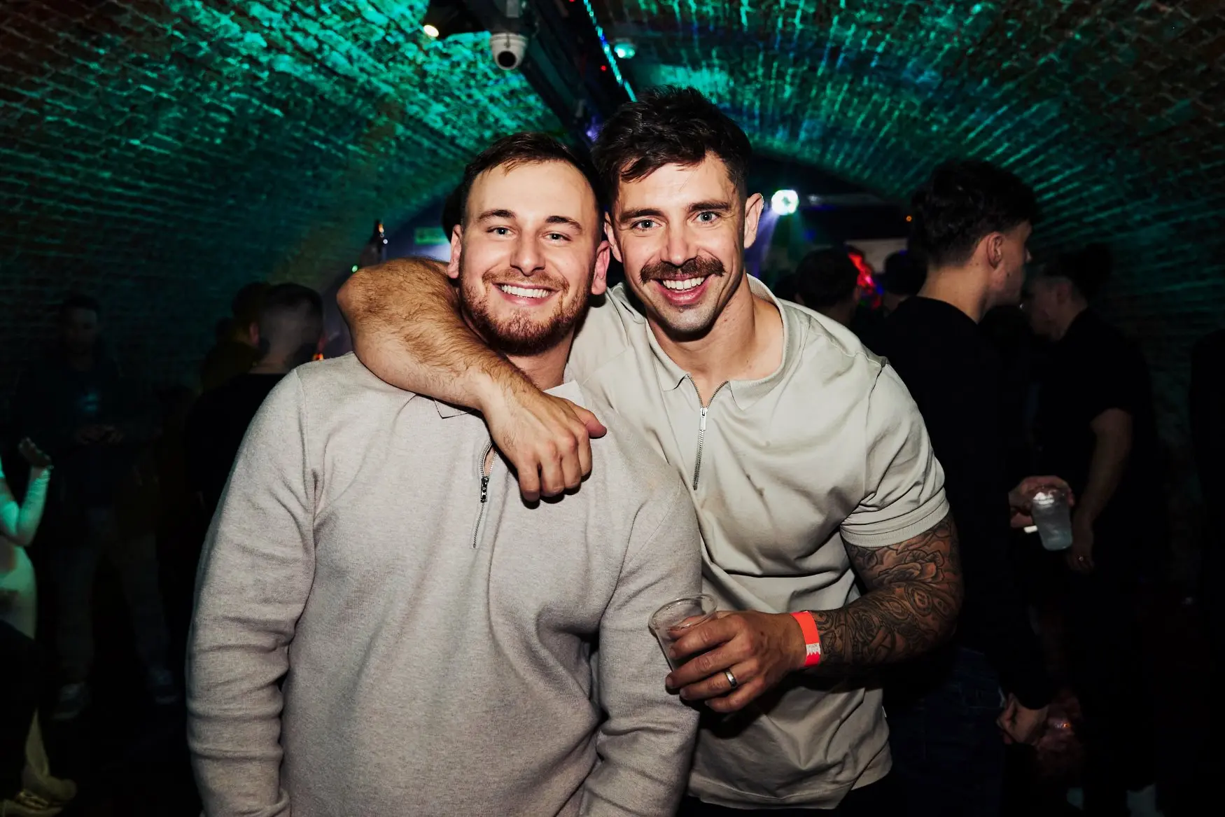 A pair of smiling male friends pose for a photo in the nightclub
